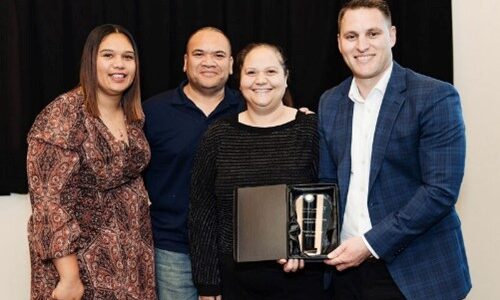 Four people smiling. One person is holding an award.