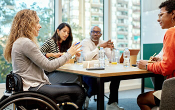 A women in a wheelchair talks to a diverse group of professionals