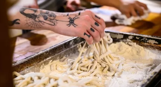 A close up of a hand making pasta.