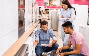 Three people in a white ware shop looking at a instruction booklet.