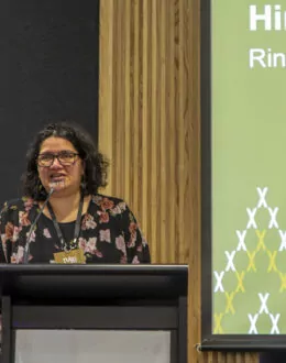 A close up of a wahine Māori (Māori women) doing a presentation. They are standing in front of a podium.